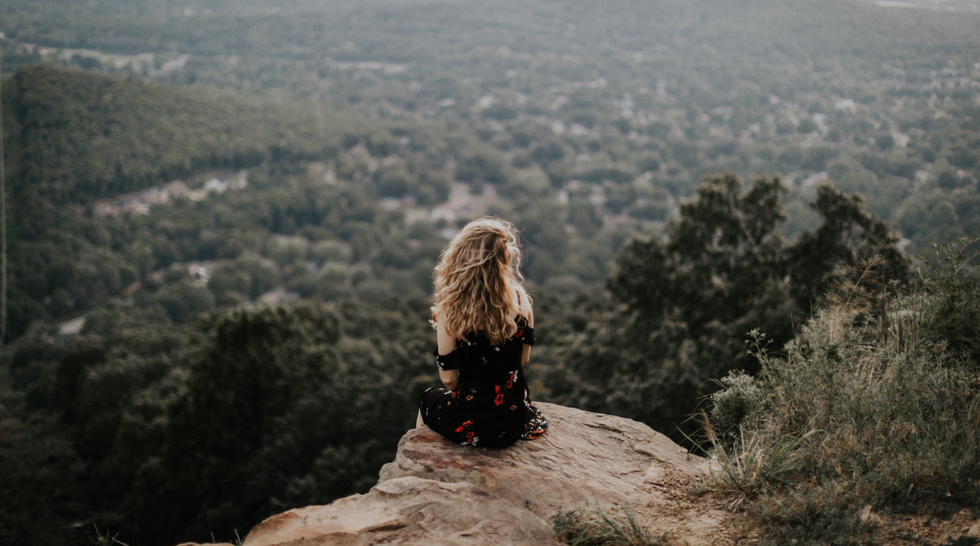 person sits on a mountaintop pondering life