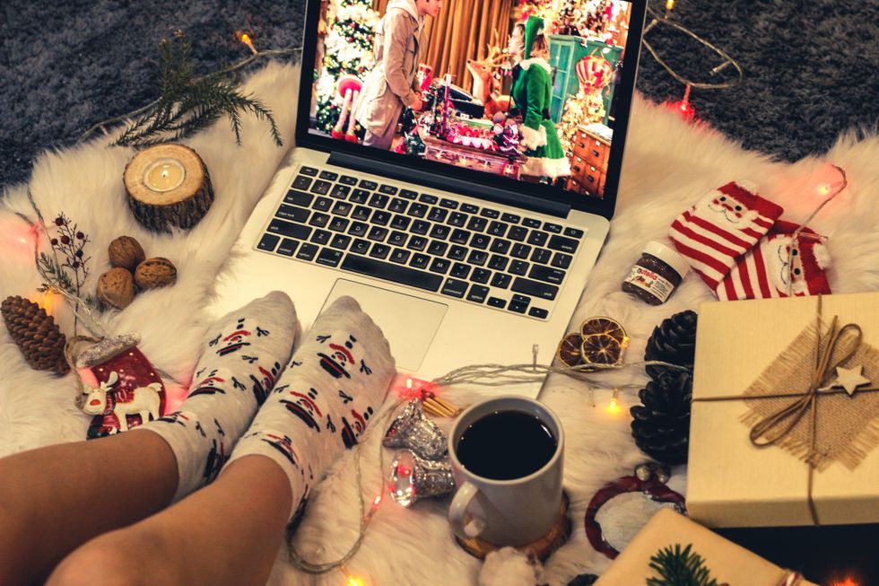 person wearing holiday pajamas while watching christmas movie on laptop