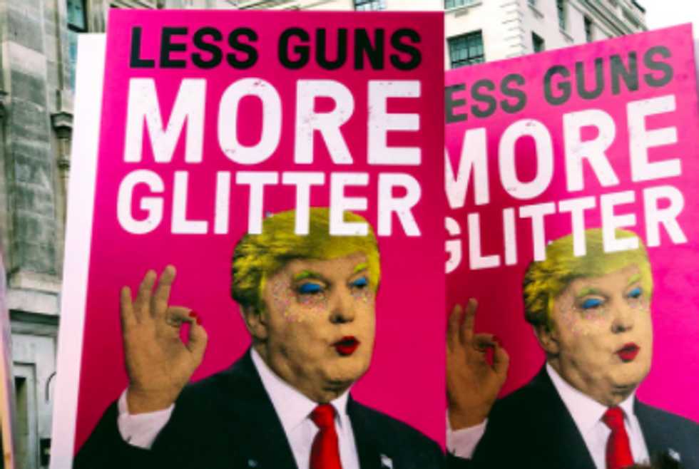 pink signs reading "less guns more glitter" with trumps face on them, painted with makeup