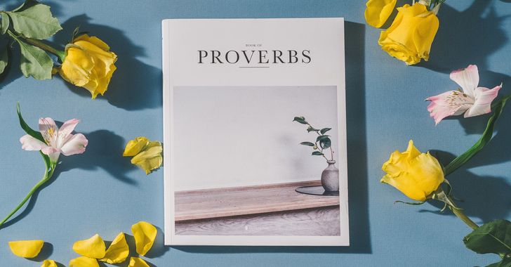 Proverbs book beside white and pink flowers