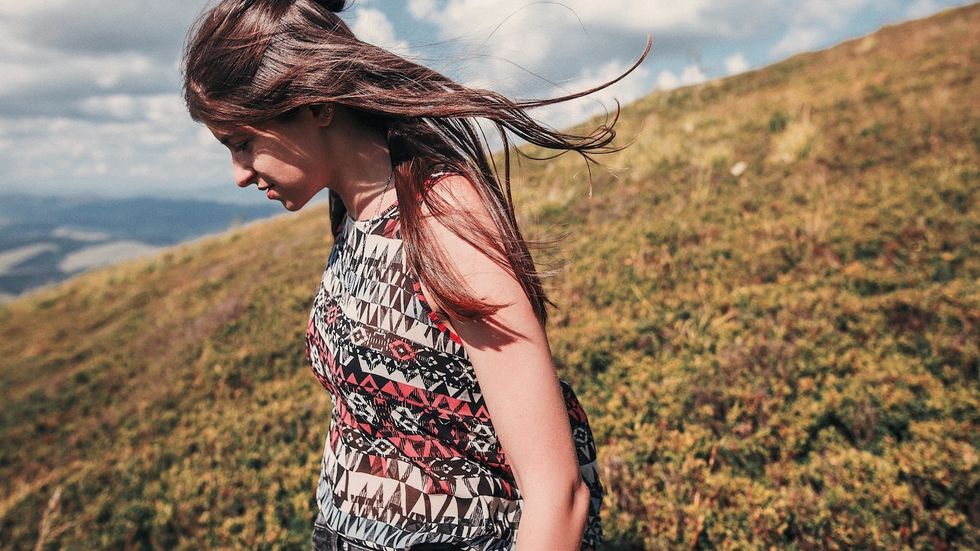 sad lonely woman walking alone in field on a mountain