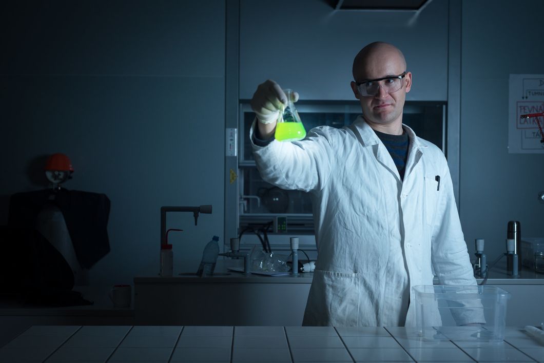 Scientist in a lab coat holding up chemicals