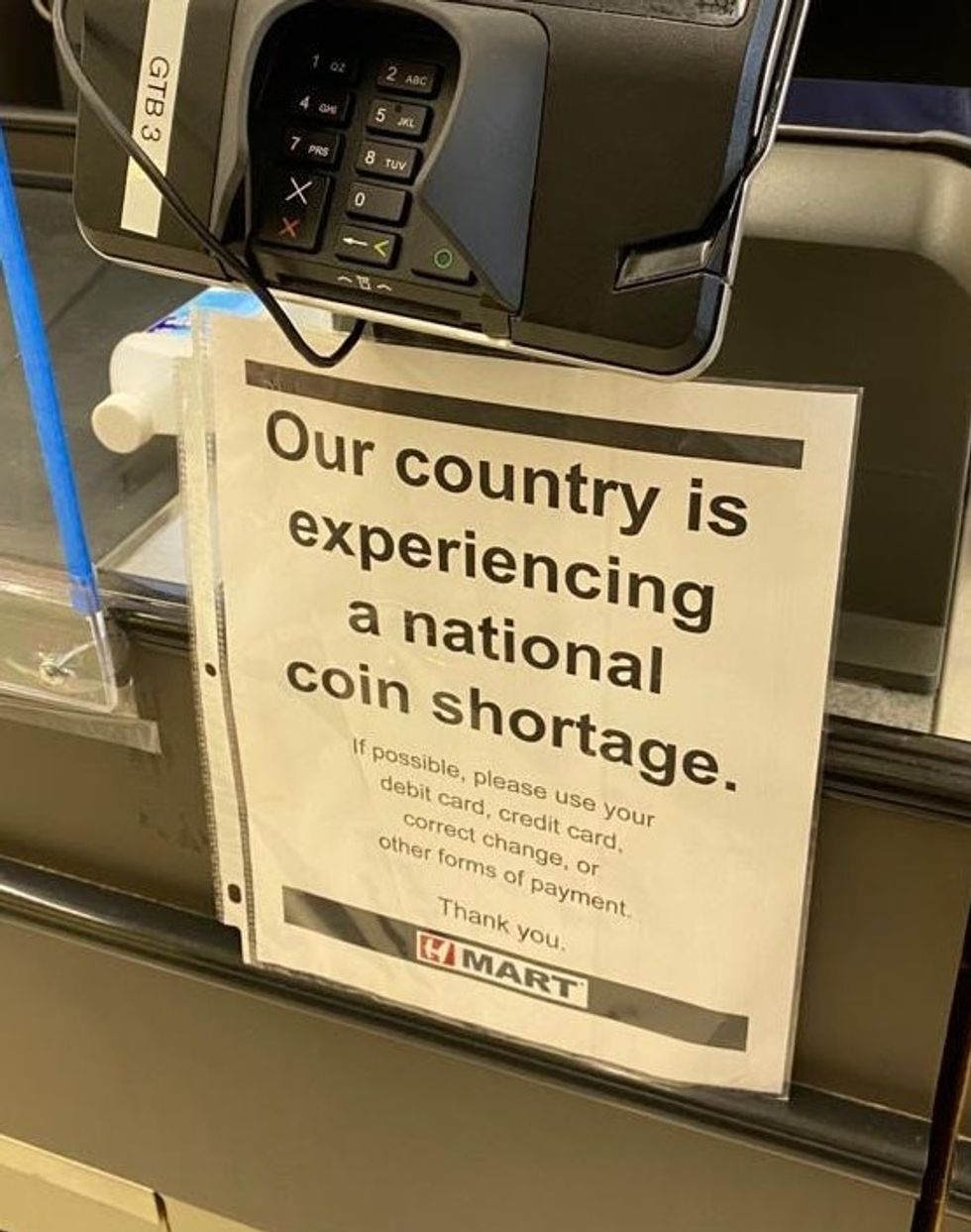 Sign under cash register which reads, "Our country is experiencing a national coin shortage. If possible, please use your debit card, credit card, correct change, or other forms of payment. Thank you."