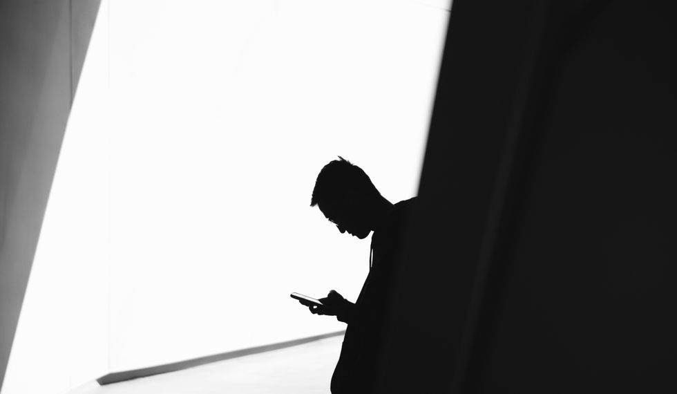 Silhouette of a guy looking down at his phone