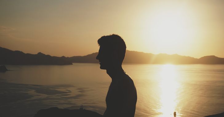 silhouette of man beside body of water during golden hour