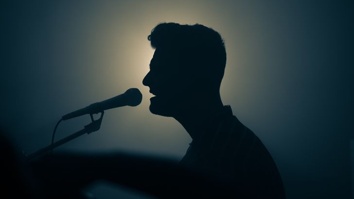 silhouette of man singing into microphone