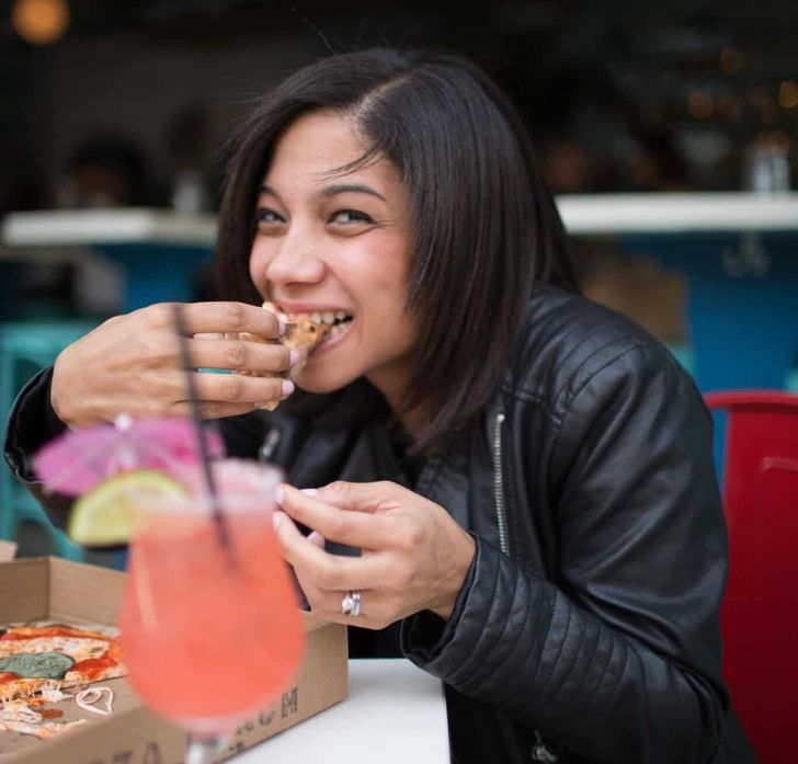 smiling asian woman eating pizza