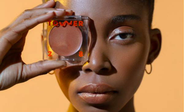 someone holding a bronzer with "tower 28" written on it over their eye