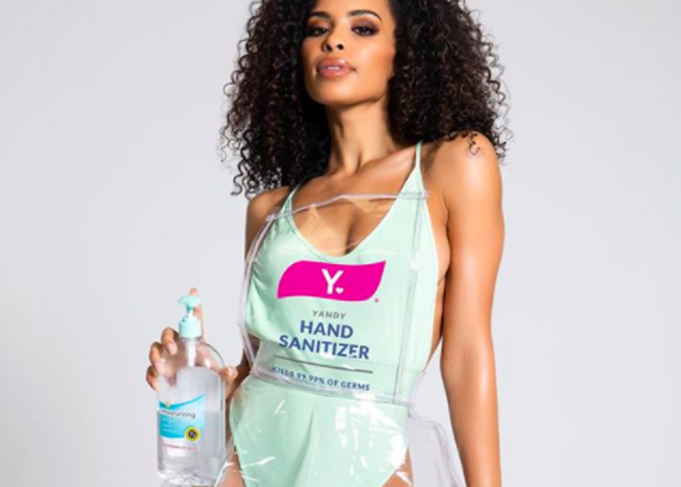 someone holding tub of hand sanitizer while wearing turqoise one-piece with "hand sanitizer" written on it