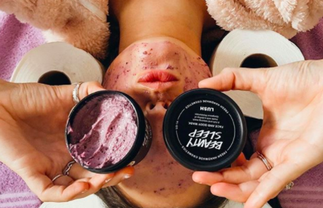 someone laying down, holding up some purple tubs of product to their eyes