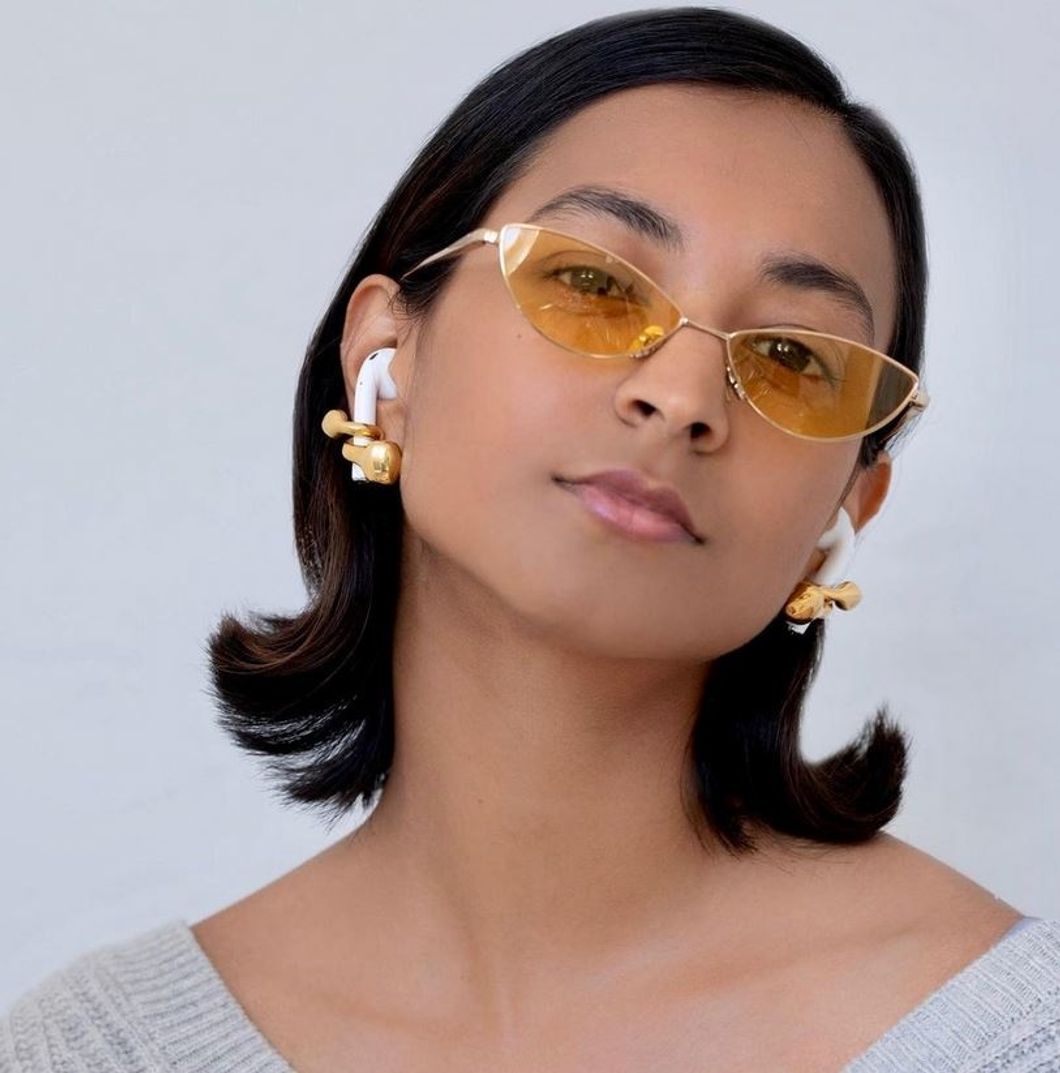 someone wearing earrings with a hole for airpods to git through them