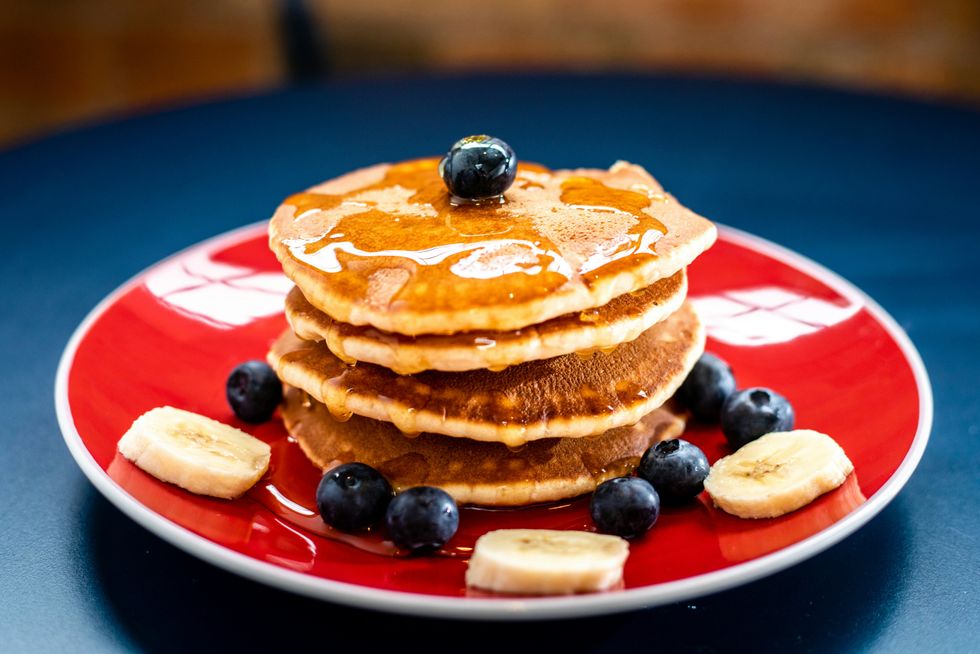 stack of pancakes with syrup, blueberries and banana