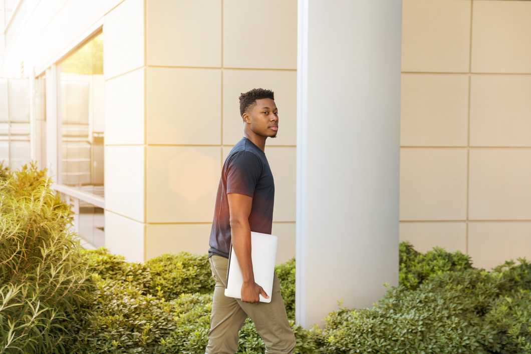 Student walking with laptop in hand