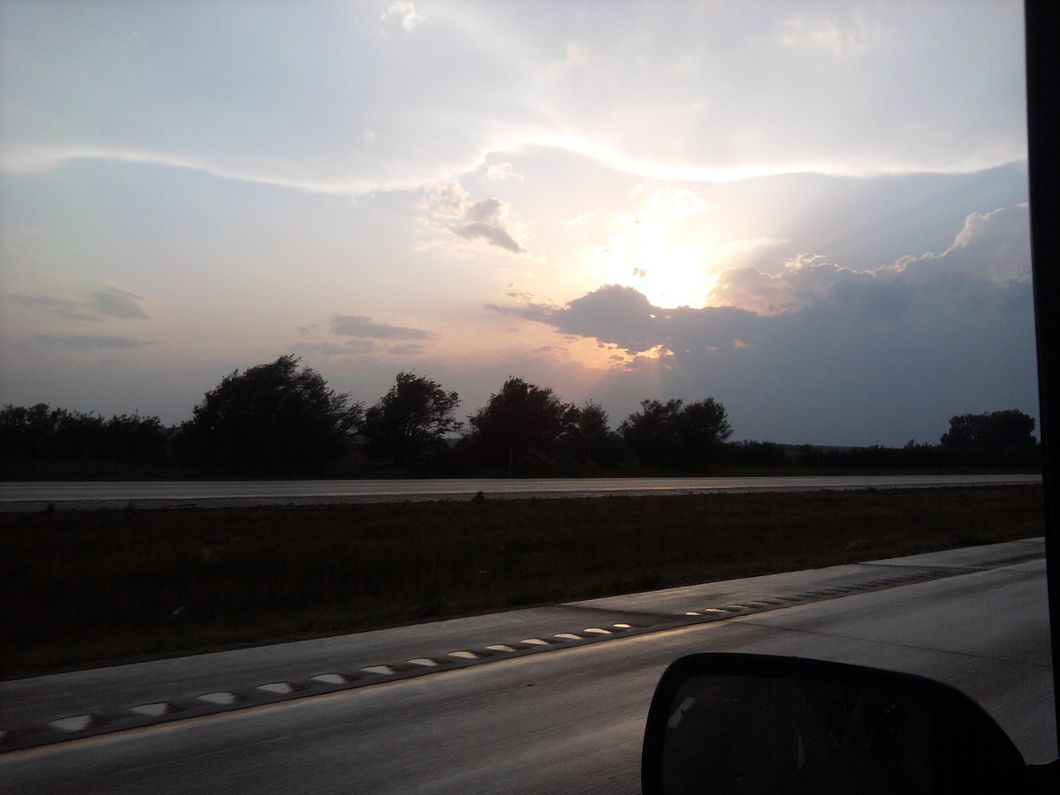 Sun breaking out from behind a cloud as seen through a car window 