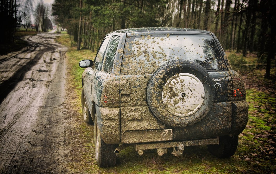 SUV on side of dirt road in small town playing country songs