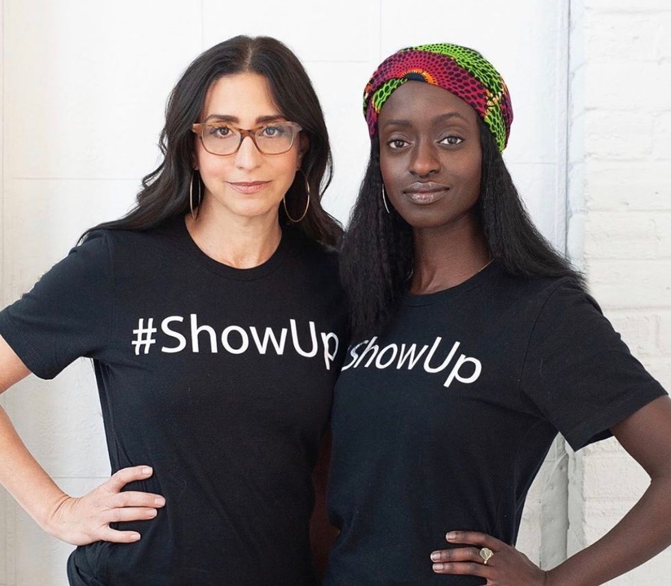This is an image of a white and black women standing in unity about ending racism and #showup for people of color.