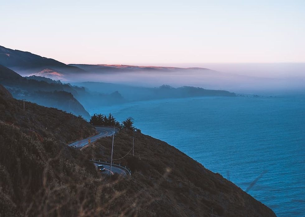This is an image of a winding highway on the coastline at dusk.