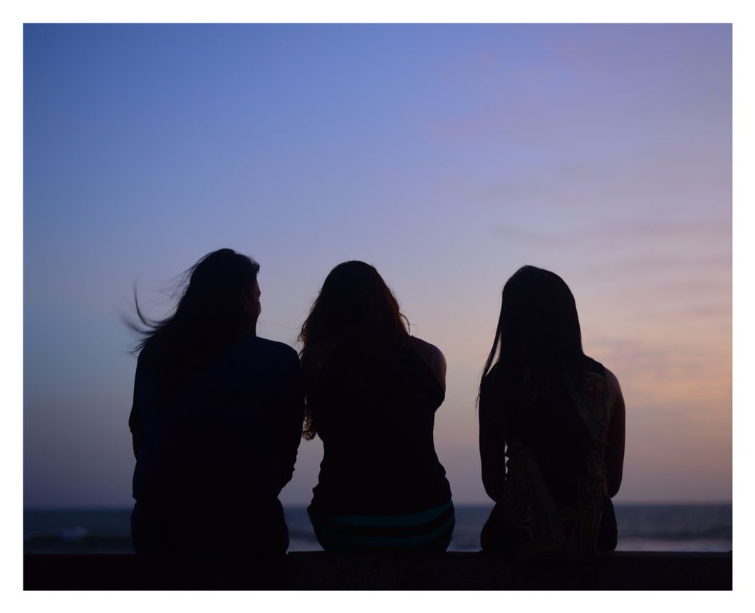 three friends at sunset silhouettes