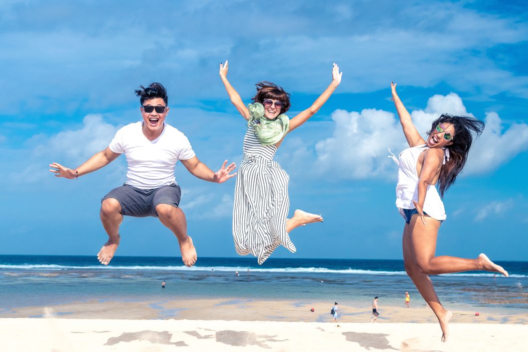 Three people jumping for a photo on the beach