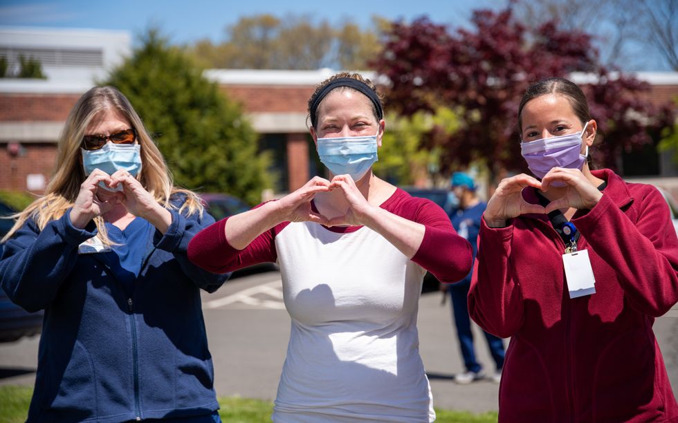 three women making a hear shape with their hands and wearing faceb