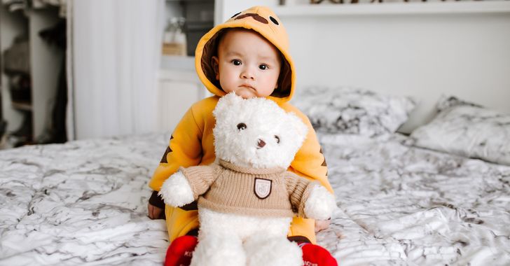 toddler sitting on bed with teddy bear
