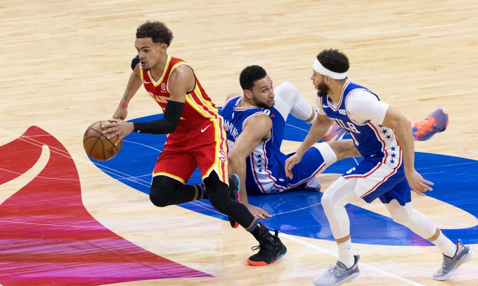 Trae Young (11), dribbling past Ben Simmons (25), and Seth Curry (31)
