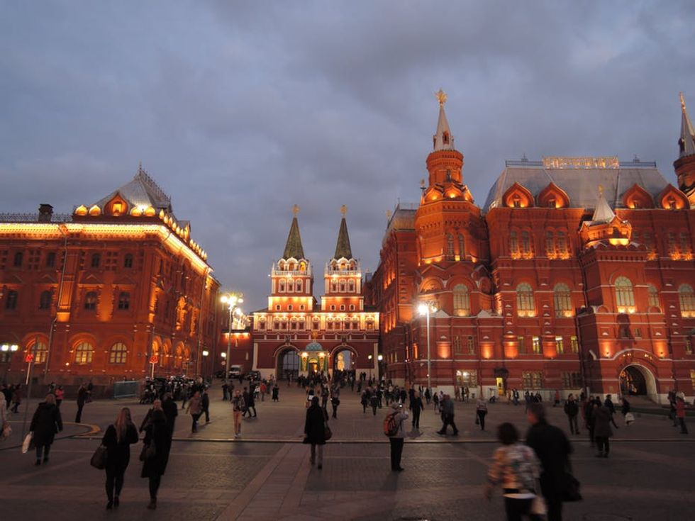 Twilight scene with people and illuminated historical buildings in view.