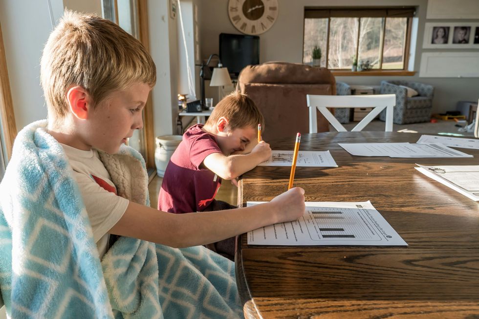 two boys sat at a table doing homework