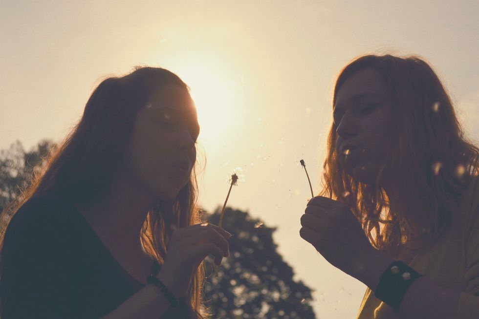 two girls blowing dandelions