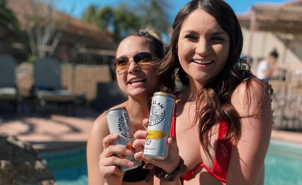 two girls smiling and holding white claws