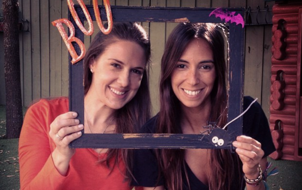 two girls smiling holding empty frame that says "boo" on it
