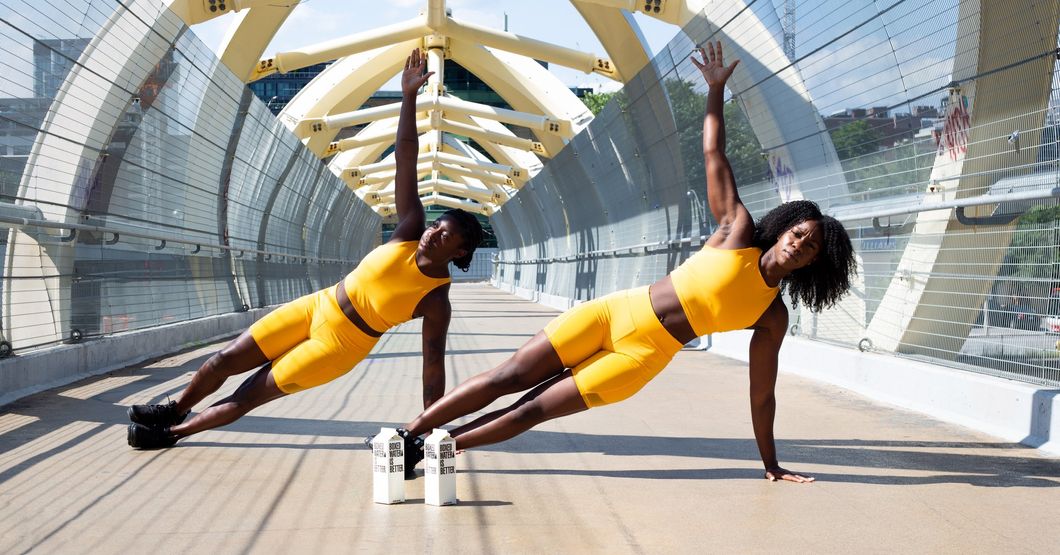 Two woman on thier hands and feet raised above the floor in yellow shorts and shirts