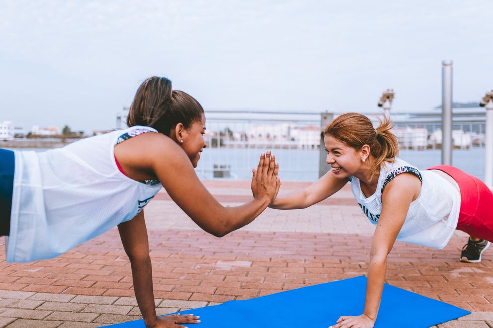 two women high five as they workout together doing yoga