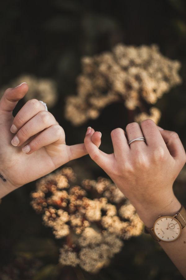 Two women's hands with their small fingers interlocking