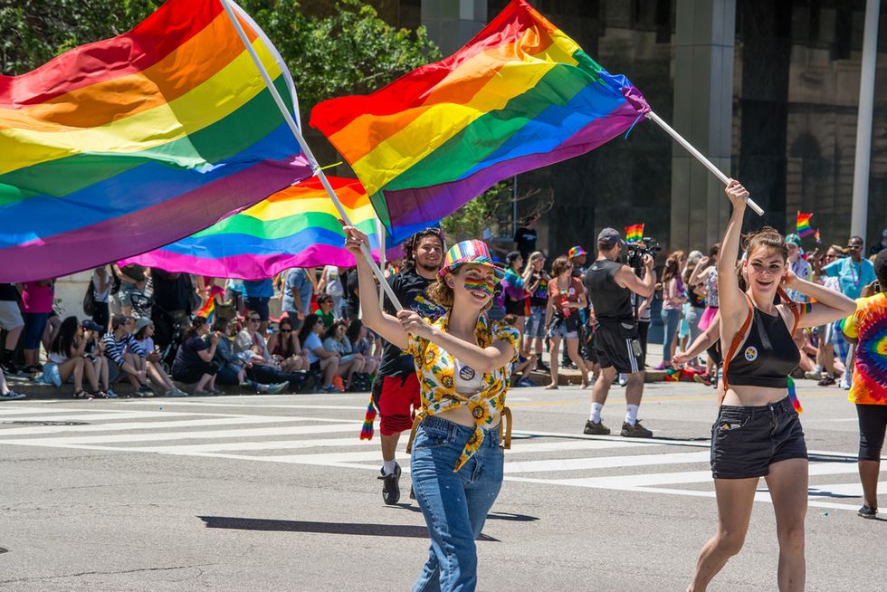 two women waving gay pride flags at lgbt pride month parade