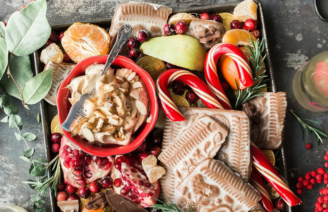 variety of sliced fruits, cookies, and chocolates on gray steel tray