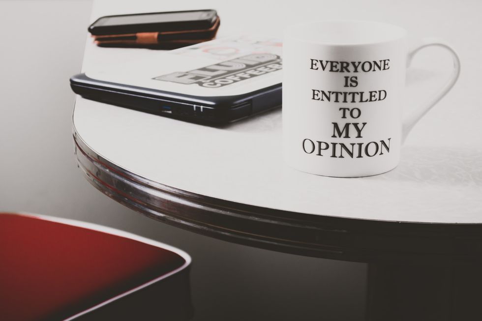 white ceramic mug on table that says everyone is entitled to my opinion