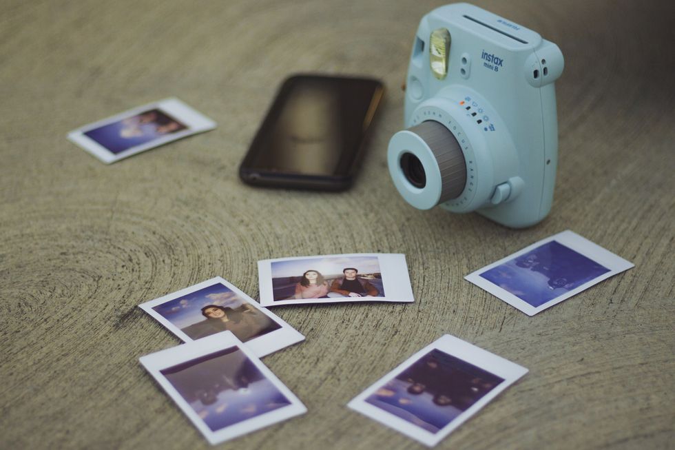 White Instax camera beside printed photos.