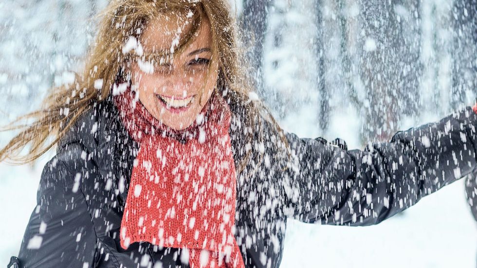 woman blowing on snow in hands