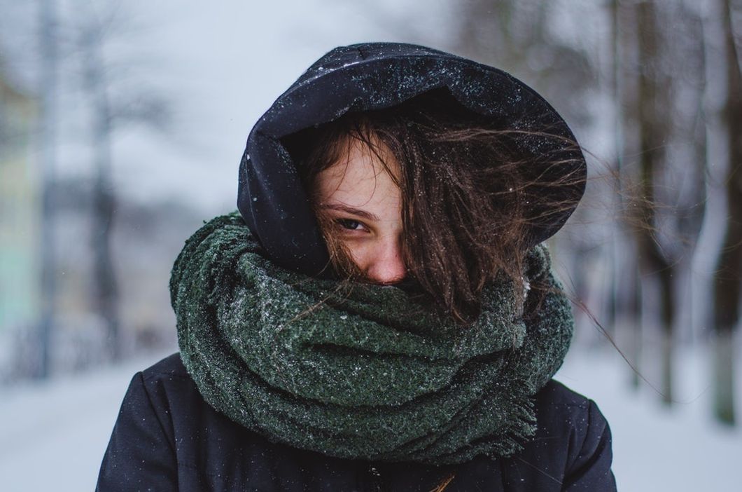 woman covered in jacket and scarf in the snow