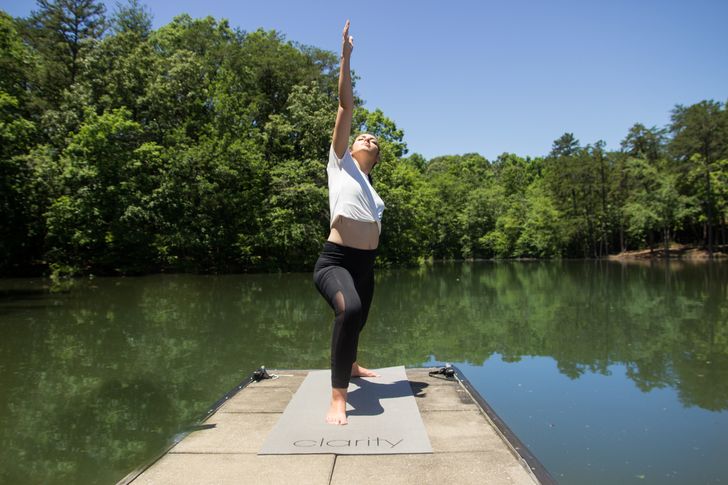 woman doing yoga near pond of water