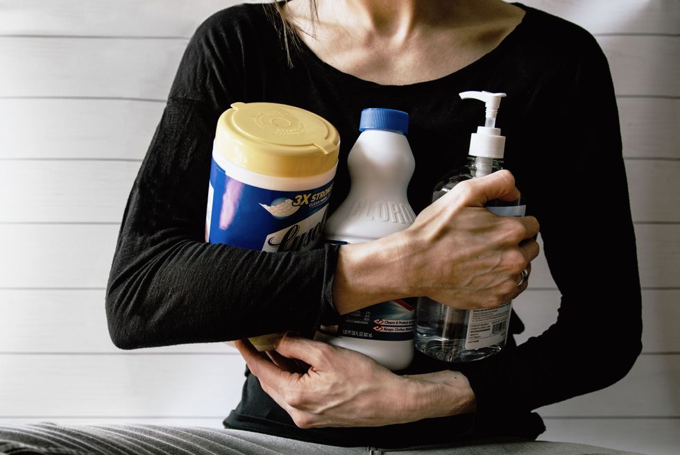 woman holding cleanning products anxiously.