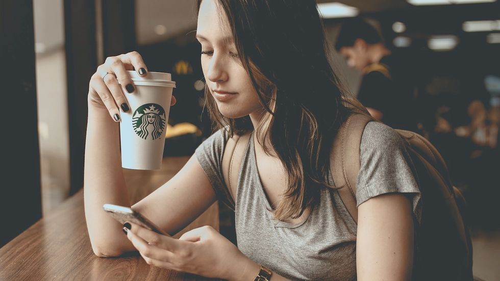woman holding coffee texting on apple iphone smart phone