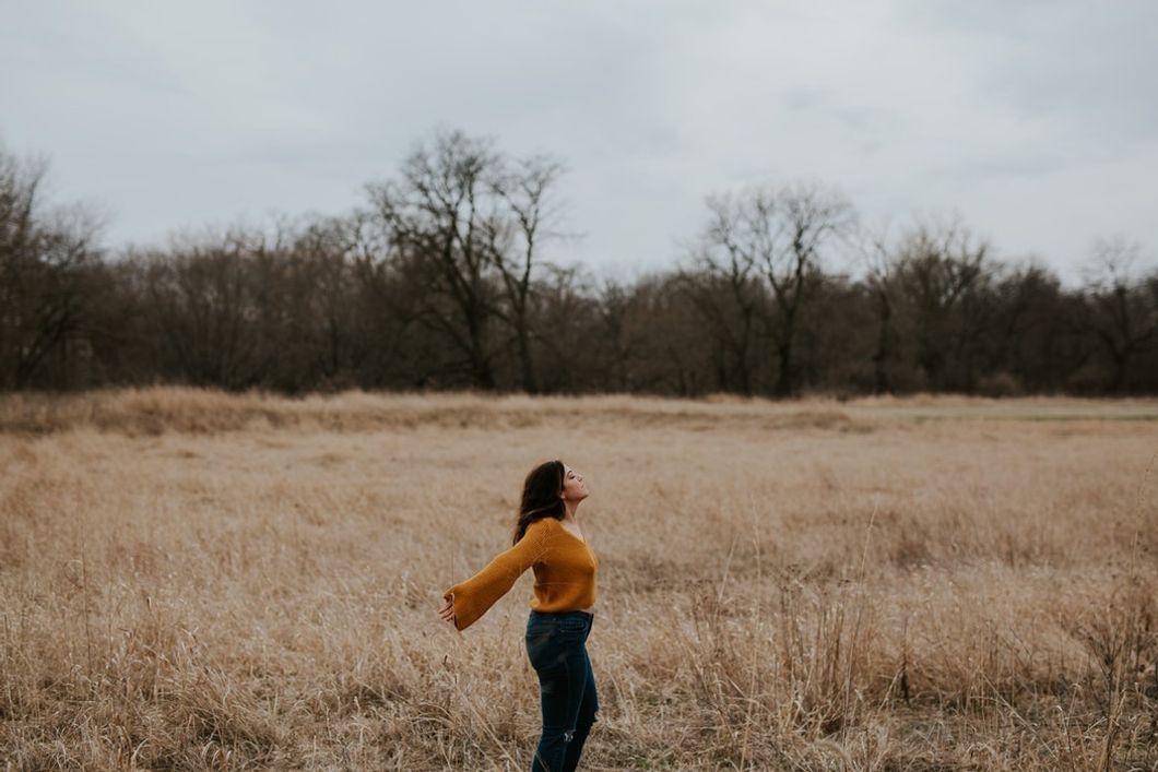 woman holding out arms in middle of field
