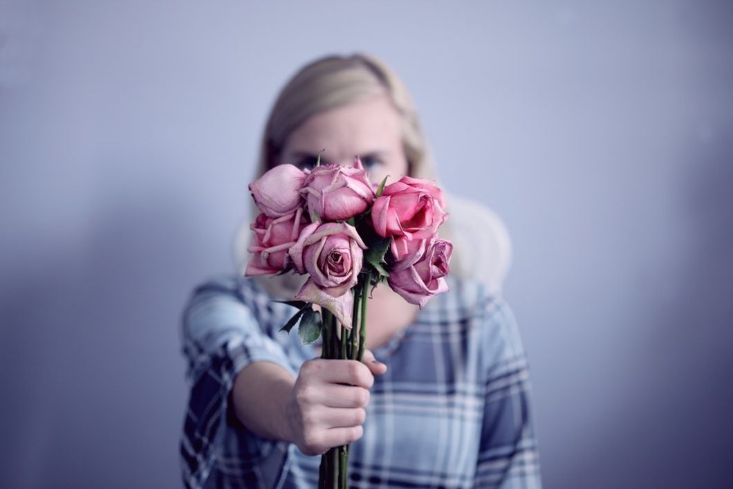 woman holding out bouquet of roses in front of face