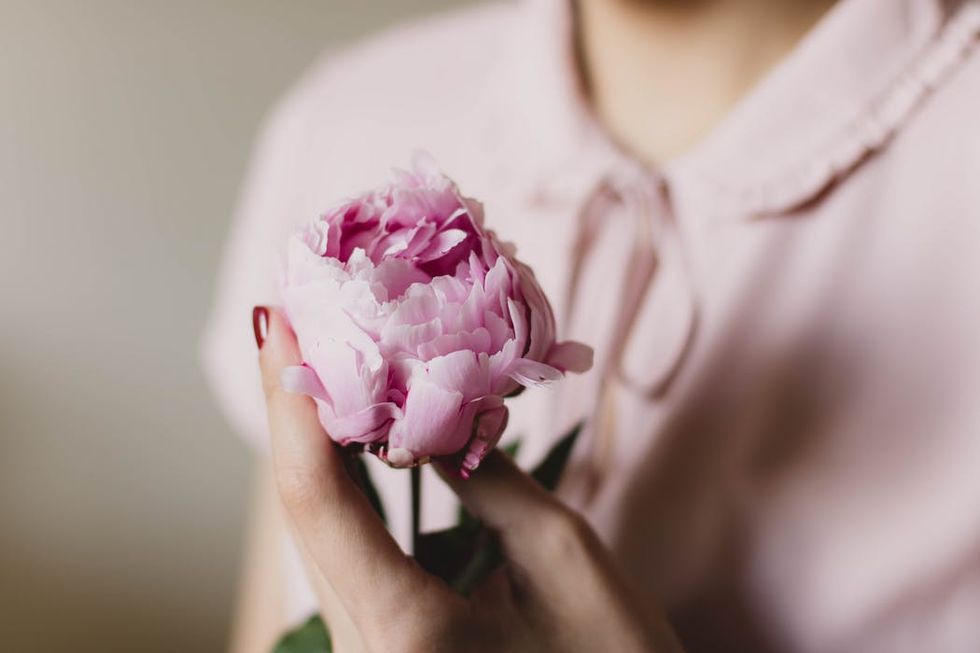 woman holds pink flower
