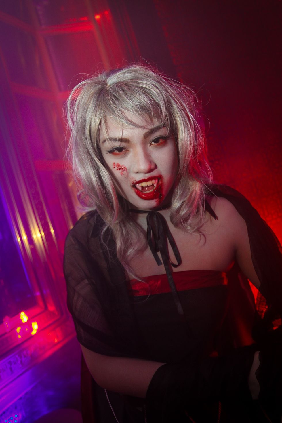 Woman in a vampire costume smiling at night