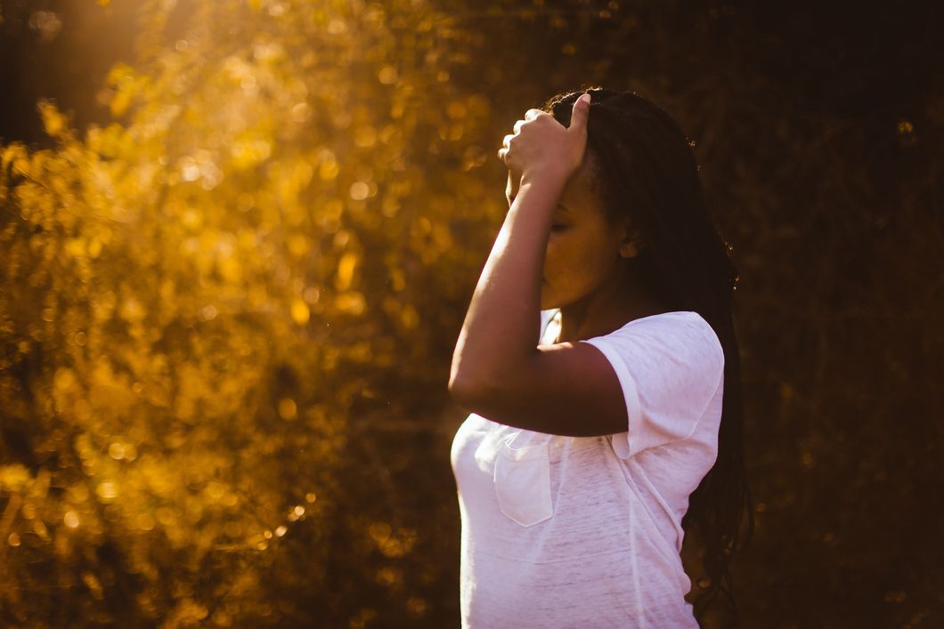 Woman in a white shirt holding her forehead