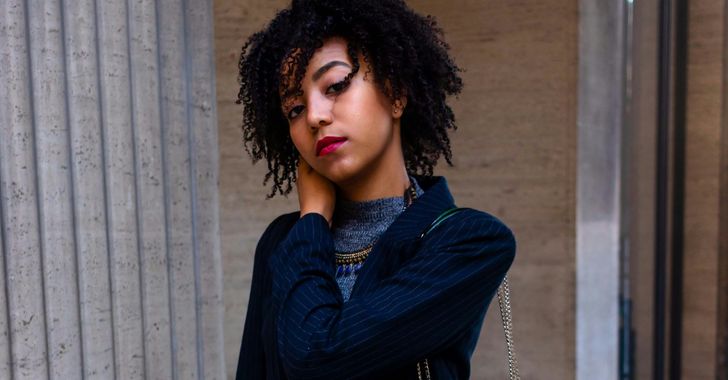 woman in dark-blue blazer carrying green purse
