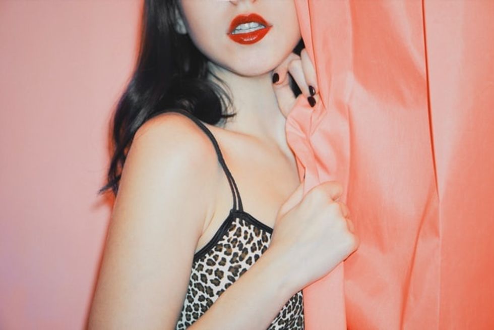 woman in leopard print spaghetti strap top holding pink silk fabric